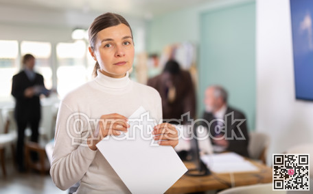 Upset woman holding documents in office