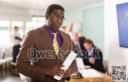 Upset african man with documents in office