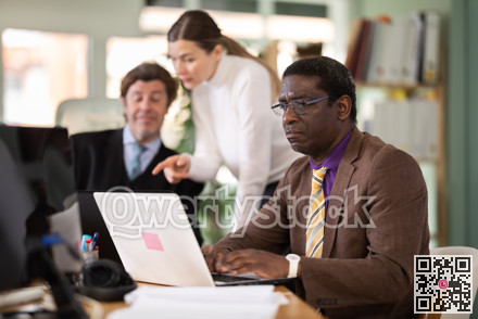 African man sitting at desk is working on laptop computer. Working day in office