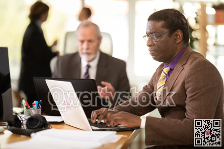 African man sitting at desk is working on laptop computer. Working day in office