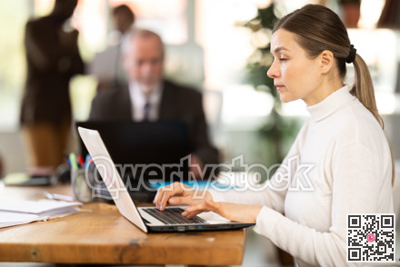 Businesswoman works in company office along with other office workers