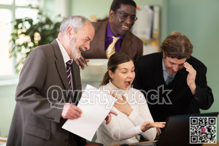 Group of colleagues look at laptop screen and laugh
