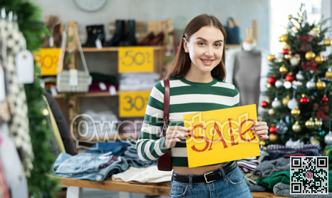 Woman with a yellow poster on sale against the background of a Christmas tree