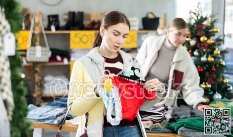 Young woman choosing panty sets on Christmas tree background in clothing store