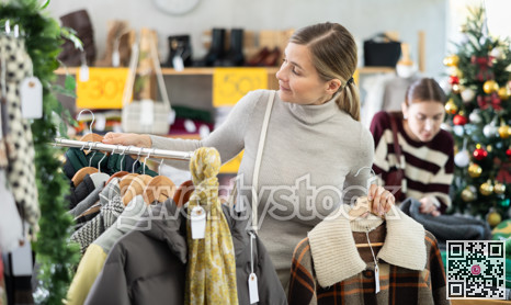 Woman client looks at products in store, choose closely plaid jacket