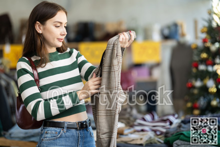 Young woman choosing trousers in clothing store