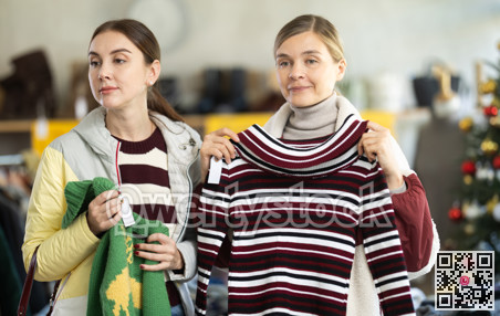 Two selective women choosing sweater in clothing store