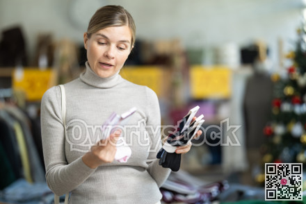 Surprised young woman choosing socks in clothing store