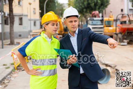 Male and female builders talking in construction site