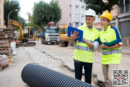 Two engineers are discussing an important project, holding a laptop and an estimate