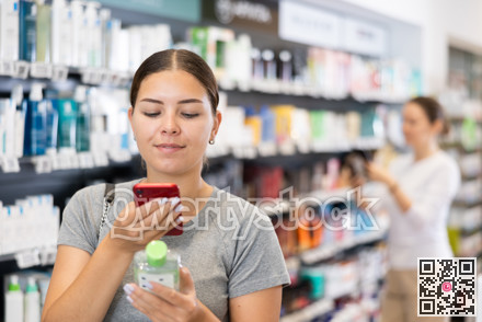 Woman shopper scanning a barcode on a cosmetics package with her phone. Searching for information via Internet