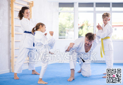 Judo or jiu jitsu classes - family with two children practicing grabbing and throwing on sports mats