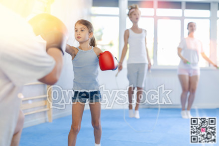 Girl with her trainer father at gym. Boy wearing boxing gloves exercise and punch to pads for boxing