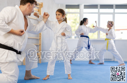 Preteen girl working on punches in sparring with father at martial arts training