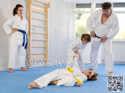 Preteen girl in kimono practicing throws in sparring with brother at family training