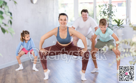 Happy middle-aged woman practicing dance movements with her family members
