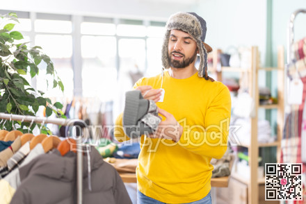 Young man choosing hat in clothing store