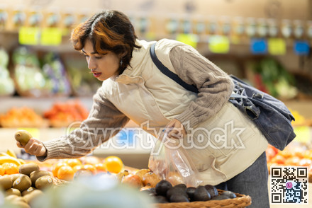 Girl near vegetable stand in store choose mango.
