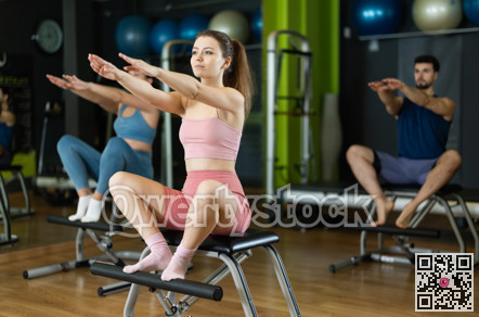 Woman doing arm and leg exercises on chair in Pilates class