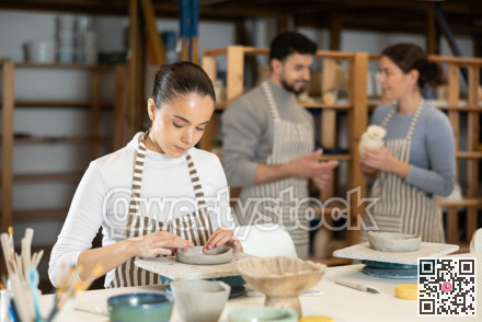 Young female pottery workshop workers sculpt from raw clay