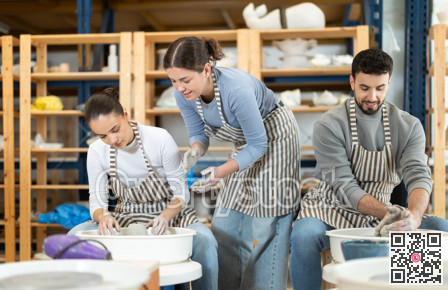 Woman help girl sculpting ceramic product from raw clay on pottery wheel in workshop
