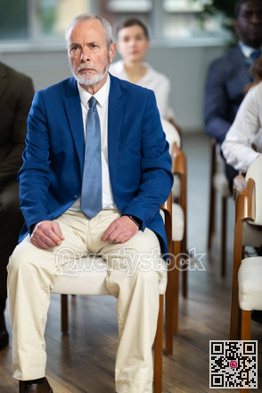 Eldery man listens to presentation in conference room