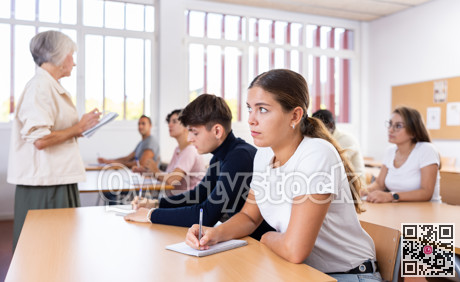 Interested girl listening and taking notes of lecture in university