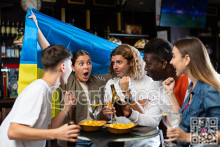 Emotional people waving flag of Ukraine while watching football match in sports pub