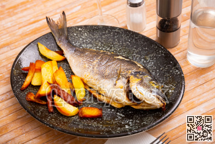 Baked dorada fish with vegetable garnish of fried potatoes