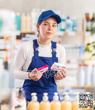 Young woman worker chooses paracetamol at pharmacy