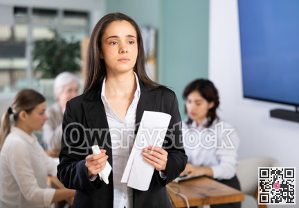 Sad young woman holding document in office