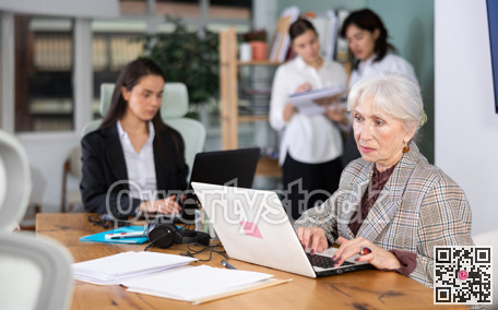Elderly woman works on laptop with female colleagues