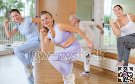 Active middle-aged woman practicing aerobic dance in training hall