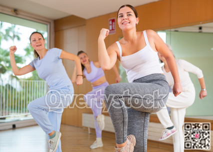 Active young woman practicing aerobic dance in training hall