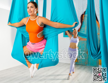 Aerial yoga in hammock. Slim woman performs gravity yoga and stretching exercises. Healthy lifestyle concept