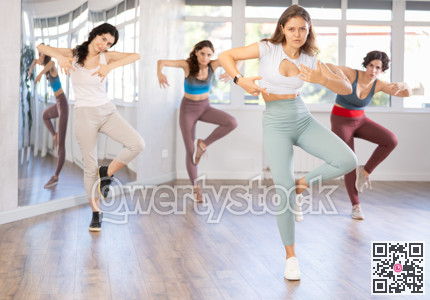 Slim women performing contemporary dance in damce studio