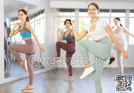 Young female teacher conducts modern dance lessons for group of girls