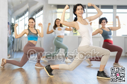 Young female teacher conducts modern dance lessons for group of girls