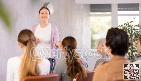 Female teacher giving lecture to group of students in classroom
