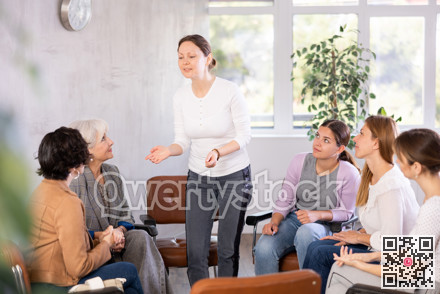 In classroom,girl stands next to colleagues and tells audience her vision of situation