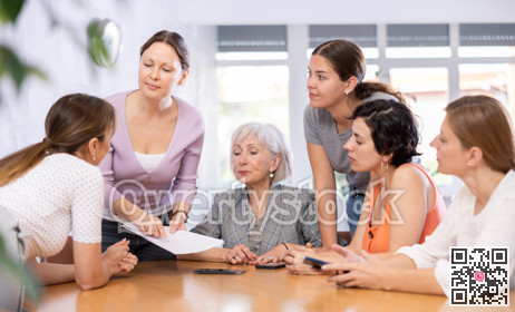 Women discuss documents sitting at table in office