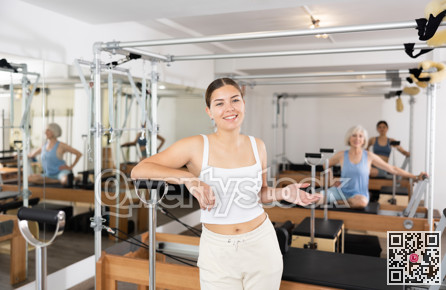 Friendly young female fitness instructor inviting to pilates studio