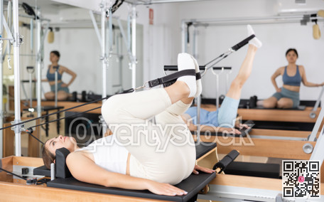 Woman engaging in pilates training on reformer bed in exercise room during workout session