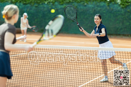 Adult woman playing doubles tennis on court