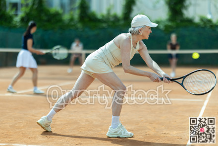 Senior female athlete plays tennis on open court with young opponent