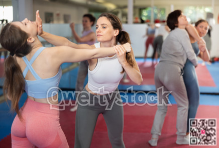 Women in pair perform effective impact on pain points while learning self-defense.