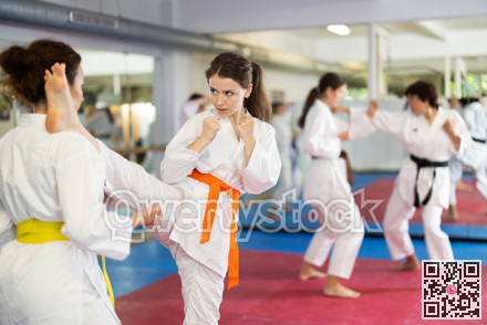 Womens practicing new karate moves in pairs in class with trainer