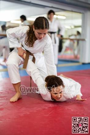 Womens practicing new karate moves in pairs in class with trainer