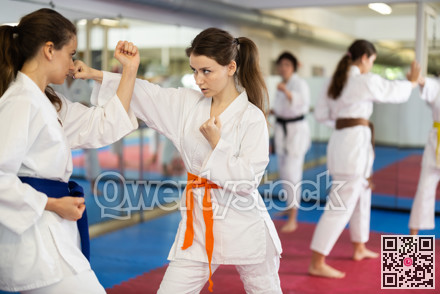 Womens practicing new karate moves in pairs in class with trainer