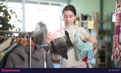 Woman in a store chooses underwear and panties, comparing different models and studying a tag. Armenian woman buys a set of casual panties